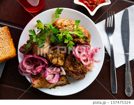 Portion of pork shashlik with greenery and onion 137475324