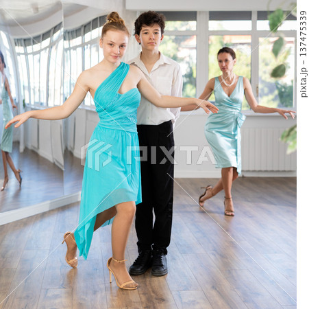 Dance teacher teaches a girl and a boy couples ballroom dancing 137475339