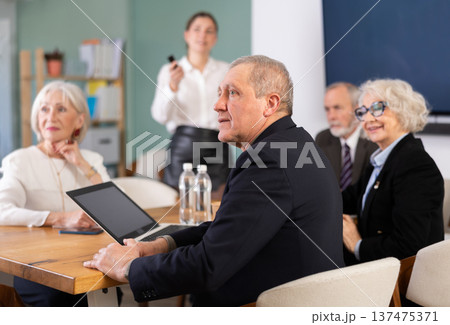 Young woman gives presentation to group of eldery employees 137475371