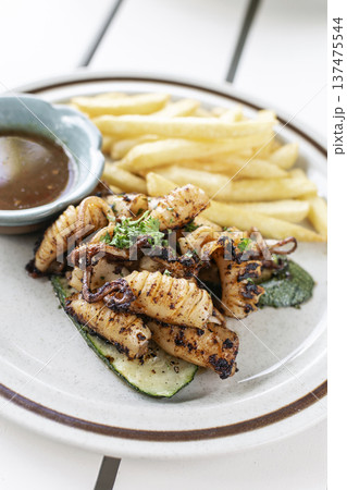 mediterranean style grilled squid with escabeche sauce and fries on white table at ibiza spain restaurant 137475544
