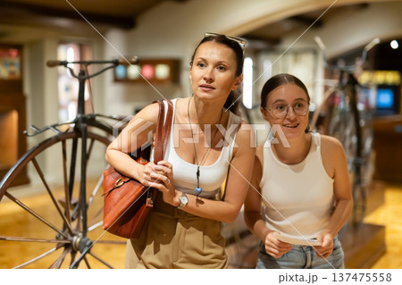 Woman and teenage girl looking at vintage bicycles in museum Woman and teenage girl looking at vintage bicycles in museum 137475558