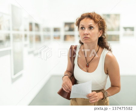 Woman observing photographs on display in photo gallery Woman observing photographs on display in photo gallery 137475582