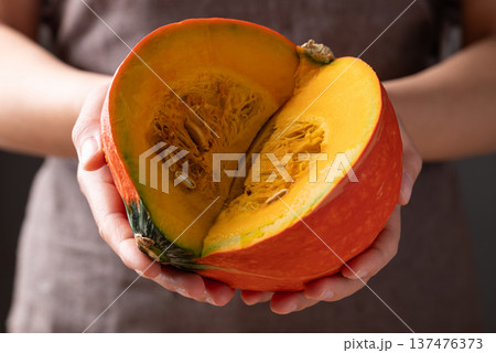 Hands holding sliced orange Kuri squash (Hokkaido pumpkin) prepare for cooking Hands holding sliced orange Kuri squash (Hokkaido pumpkin) prepare for cooking 137476373