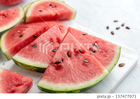Freshly Sliced Watermelon Pieces on White Marble Surface with Seeds and Juicy Flesh Freshly Sliced Watermelon Pieces on White Marble Surface with Seeds and Juicy Flesh 137477071