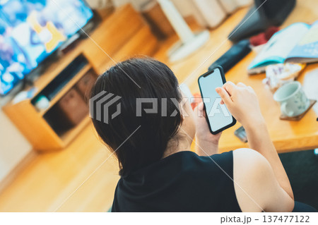 テレビ見ないでスマホを見る40代女性 137477122