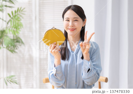 財布を持ってピースする女性 137478330