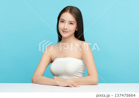 A beautiful young Asian woman with clean, fresh skin against a blue background. Skincare, facial treatment, cosmetology, beauty, and spa. An elegant portrait of an Asian woman. A beautiful young Asian woman with clean, fresh skin against a blue background. Skincare, facial treatment, cosmetology, beauty, and spa. An elegant portrait of an Asian woman. 137478664