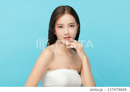 A beautiful young Asian woman with clean, fresh skin against a blue background. Skincare, facial treatment, cosmetology, beauty, and spa. An elegant portrait of an Asian woman. A beautiful young Asian woman with clean, fresh skin against a blue background. Skincare, facial treatment, cosmetology, beauty, and spa. An elegant portrait of an Asian woman. 137478666