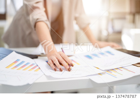 Close up of a businesswoman or office worker's hand holding pencil over document with graph or chart 137478787
