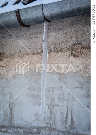 Icicle Hanging From Metal Gutter on Building Exterior 137479015
