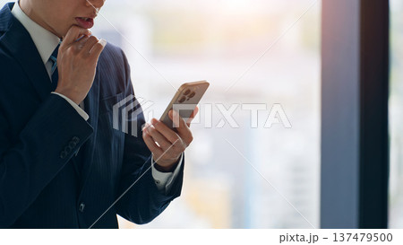 都市を背景にスマホを使う男性ビジネスパーソン 都市を背景にスマホを使う男性ビジネスパーソン 137479500