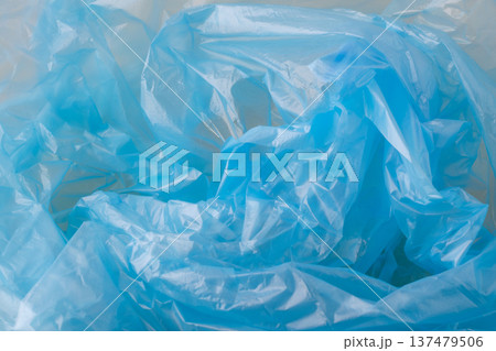 Crumpled blue plastic material forming an abstract background texture. Showing translucent, synthetic, and reusable plastic packaging Crumpled blue plastic material forming an abstract background texture. Showing translucent, synthetic, and reusable plastic packaging 137479506