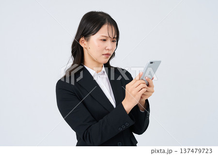 困った表情でスマートフォンの画面を見るビジネスウーマン 137479723