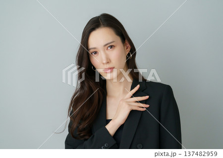 グレーバックの若い日本人女性の黒いスーツを着たファッションポートレート 137482959