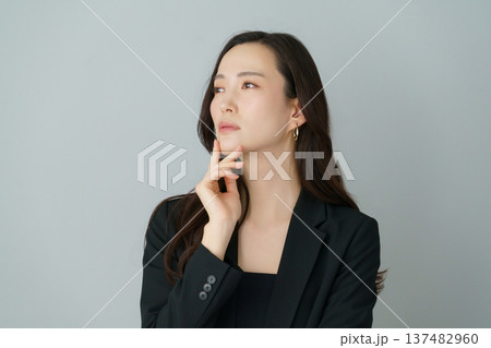 グレーバックの悩める黒いスーツを着た若い日本人女性のポートレート 137482960