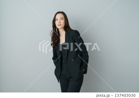 グレーバックの若い日本人女性の黒いスーツを着たファッションポートレート 137483030
