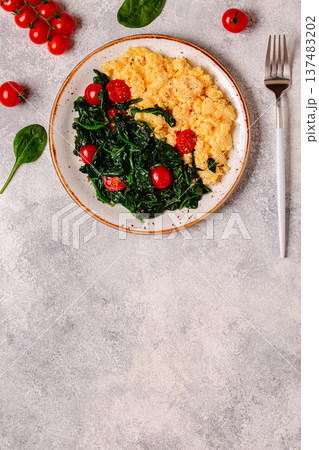 Cooked omelette and spinach with tomatoes on a light background 137483202