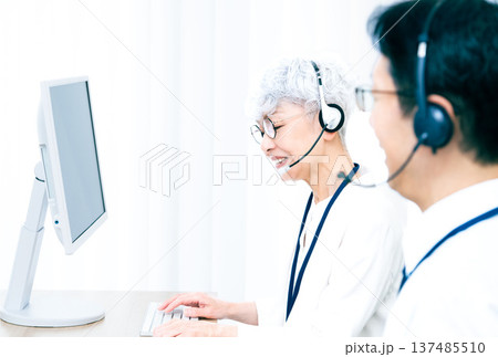 ヘッドセットをつけてパソコン操作をするシニア女性 137485510