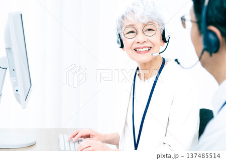 ヘッドセットをつけてパソコン操作をするシニア女性 137485514
