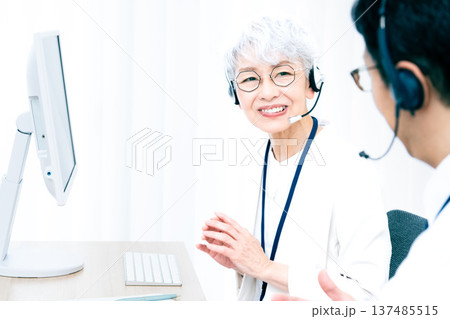 ヘッドセットをつけてパソコン操作をするシニア女性 137485515