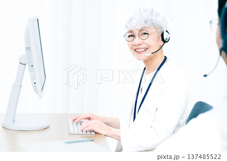 ヘッドセットをつけてパソコン操作をするシニア女性 137485522