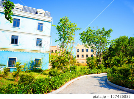 Walkway in garden area with old buildings surrounded by green plants. Pathway winds  137486885