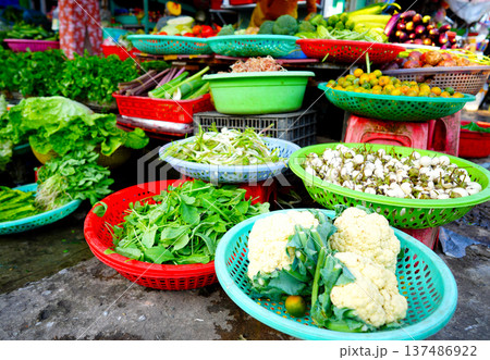 Vegetables market. Vendors display various types of fresh vegetables in baskets for sale  137486922