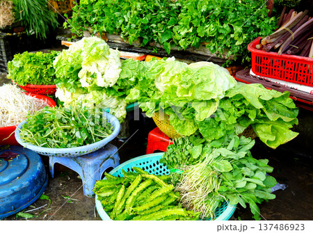 Vegetables market. Vendors display various types of fresh vegetables in baskets for sale  137486923