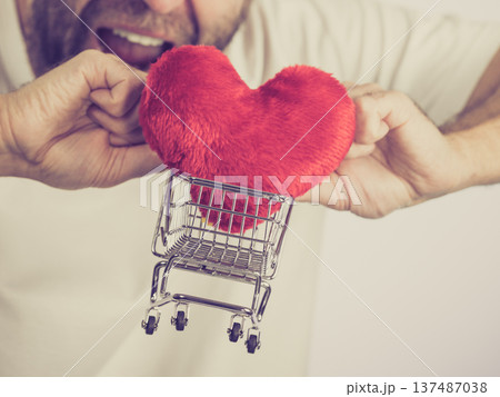 Man holds shopping cart with heart. 137487038