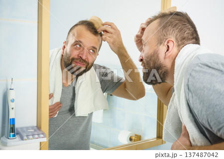 Man using comb in bathroom Man using comb in bathroom 137487042