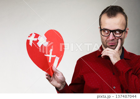 Thoughtful man holds broken heart 137487044