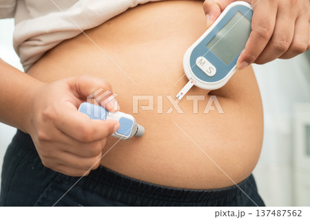 Asian woman injecting herself diabetes injecting insulin in stomach at home. 137487562