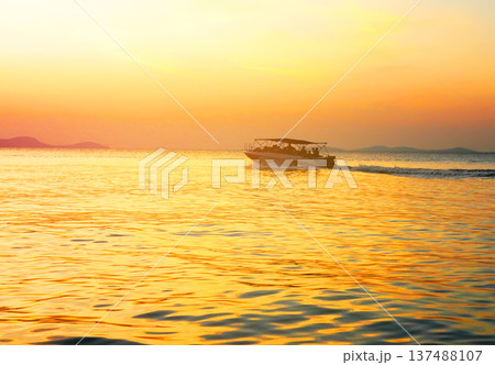 Fast motorboat carries tourists across ocean. Speedboat moves sea on sunset near coastline  137488107