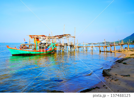 Fishing boat at wooden pier on clear blue sky, calm ocean water in daytime in coastal. Fishing boat Fishing boat at wooden pier on clear blue sky, calm ocean water in daytime in coastal. Fishing boat 137488125