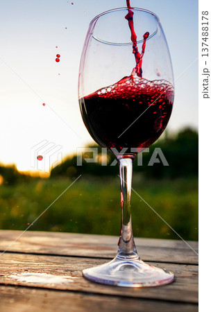 Pouring red wine into glass on winemaking. Wine poured from bottle in wine glass Pouring red wine into glass on winemaking. Wine poured from bottle in wine glass 137488178