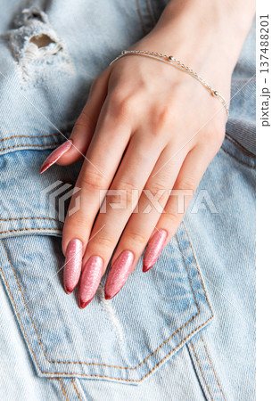 Woman's hand with stiletto nails on denim jacket 137488201