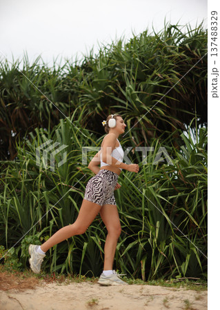 Active Woman Running. Athletic Woman Sporting Headphones And Zebra Attire Enjoying Bright Trail Run Active Woman Running. Athletic Woman Sporting Headphones And Zebra Attire Enjoying Bright Trail Run 137488329