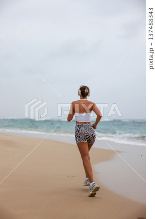 Runner On Beach. Dedicated Athlete Practices Endurance By Jogging Solitary Along Tranquil Ocean Coast 137488343