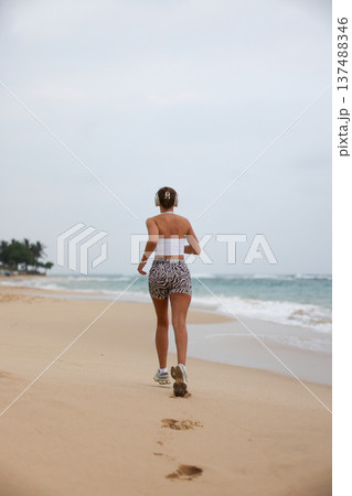 Runner On Beach. Dedicated Athlete Practices Endurance By Jogging Solitary Along Tranquil Ocean Coast 137488346