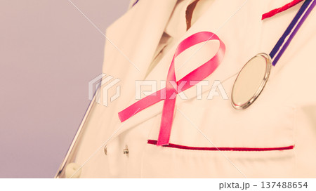 Pink ribbon with stethoscope on medical uniform. 137488654