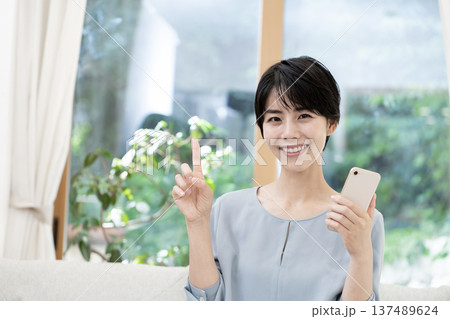 ソファーに座りスマートフォンを使う若い女性 137489624