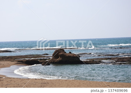霞む空と水平線と青い海面の海と岩場と岩と砂浜の海岸と波打ち際の白い波の風景 霞む空と水平線と青い海面の海と岩場と岩と砂浜の海岸と波打ち際の白い波の風景 137489696