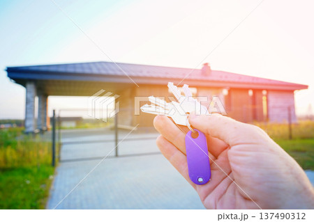 Keys to new house. Keys against of new house facade. Buying new suburb home, villa rent. 137490312