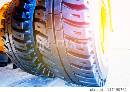 Tire for mining truck close-up. Heavy Machinery Tire background in Bright Sunlight. 137490762
