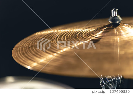 Drum cymbal close-up on a dark background. 137490820