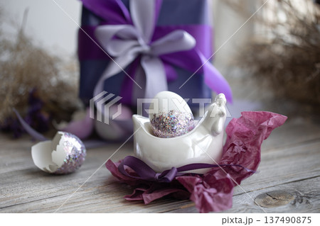 Easter composition with an egg and a gift on a blurred background. Easter composition with an egg and a gift on a blurred background. 137490875