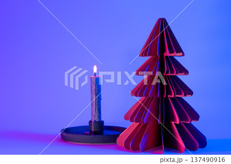 Decorative paper Christmas tree and candle on blue background with trendy neon light. Decorative paper Christmas tree and candle on blue background with trendy neon light. 137490916