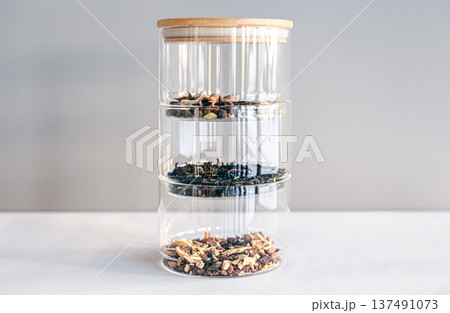 Different types of tea in glass jars on a light background, isolated. 137491073