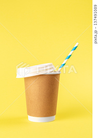 Disposable cup with a straw on a yellow background isolated. Disposable cup with a straw on a yellow background isolated. 137491089