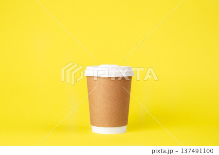 Disposable paper cup on a yellow background isolated. 137491100